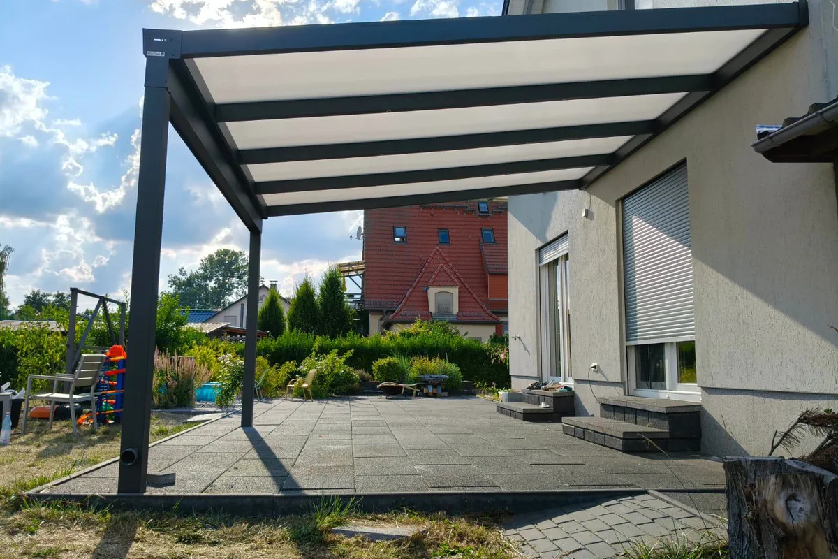 Terrassenüberdachung an einem Einfamilienhaus mit gepflasterter Terrasse