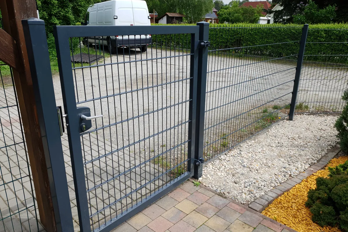 Pforte aus Doppelstabmatten an einer gekiesten Einfahrt