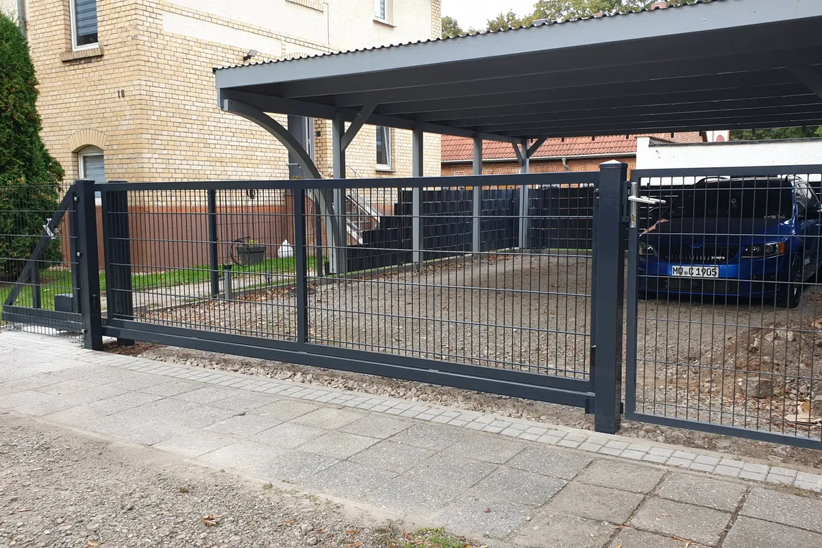 Schiebetor aus Doppelstabmatten vor einem Carport mit geparktem Auto