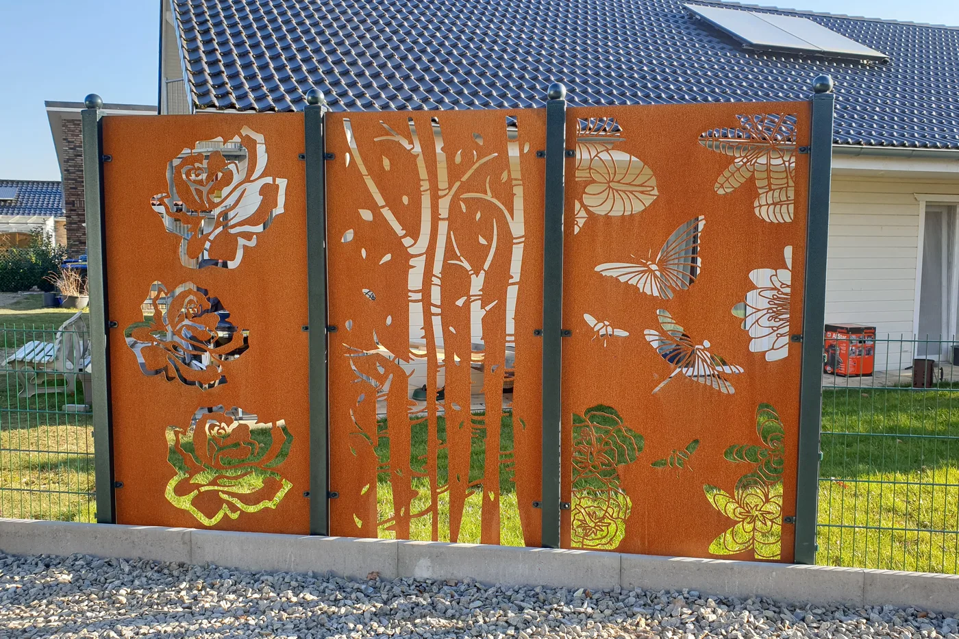 Corten-Sichtschutzpaneele mit gelaserten Motiven zwischen Zaunfeldern